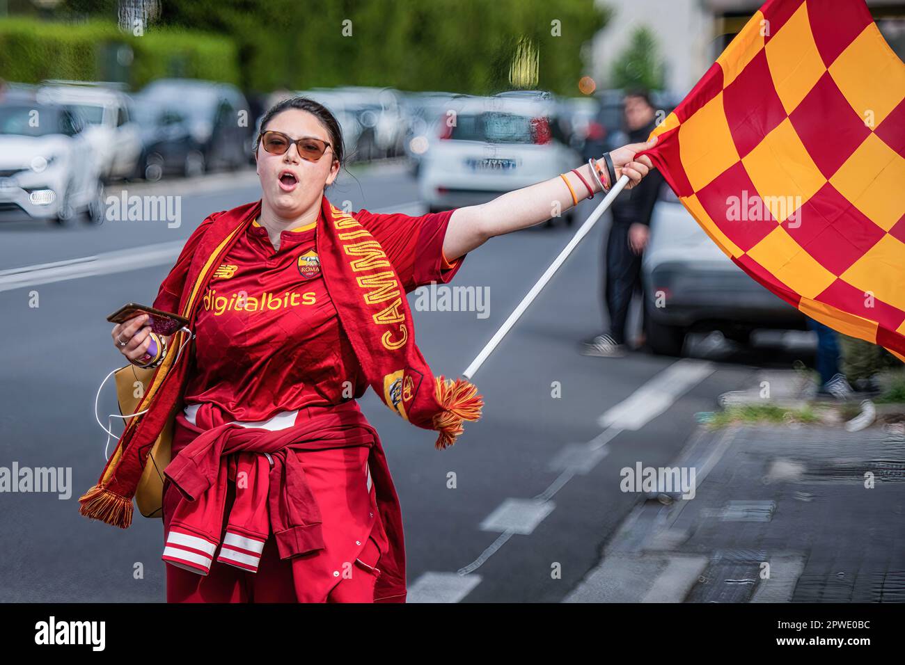 Rome, Italy. 29th Apr, 2023. A young woman dressed in AS Roma colors and AS  Roma scarf walks chanting 'i campioni siamo noi' (we are the champions)  along the street waving the