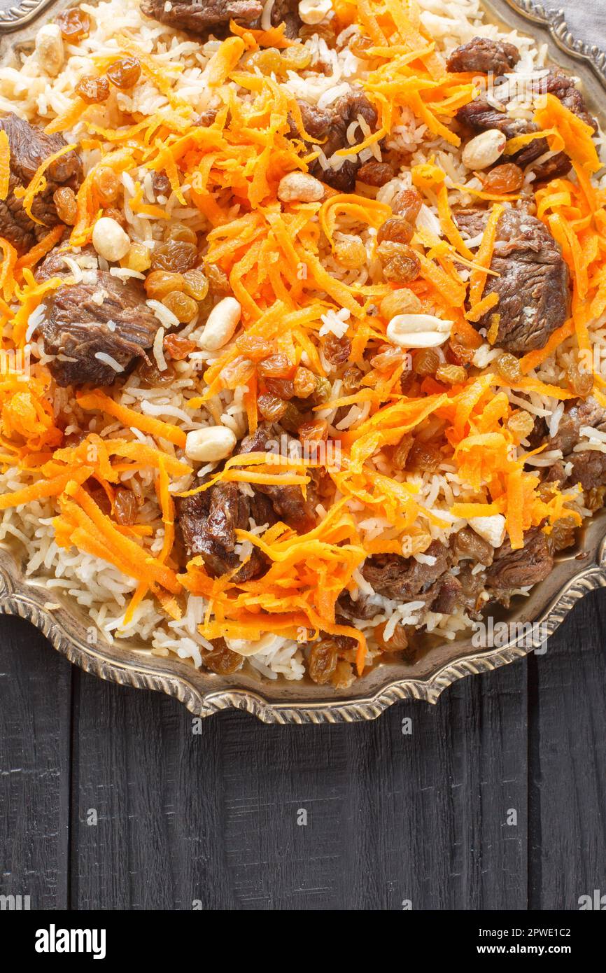 Kabuli Pulao Afghan rice and lamb pilaf closeup on the plate on the wooden table. Vertical top
