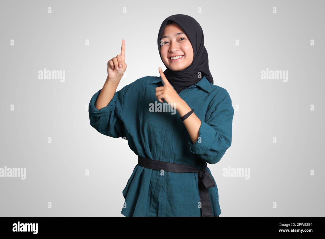 Portrait of excited Asian hijab woman in casual outfit standing against ...