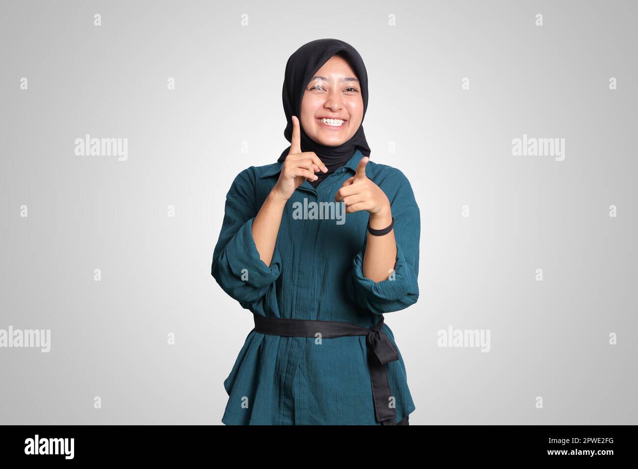 Portrait of excited Asian hijab woman in casual outfit standing against ...