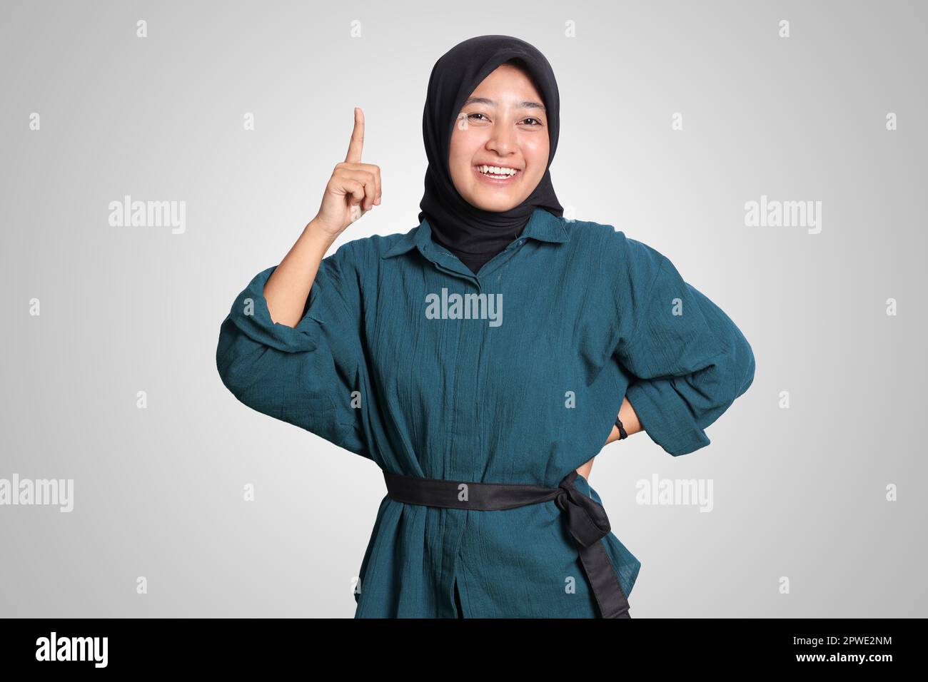 Portrait of excited Asian hijab woman in casual shirt pointing up her ...