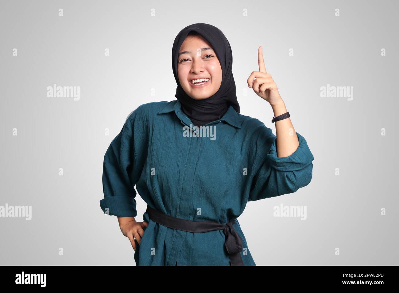 Portrait of excited Asian hijab woman in casual shirt pointing up her ...