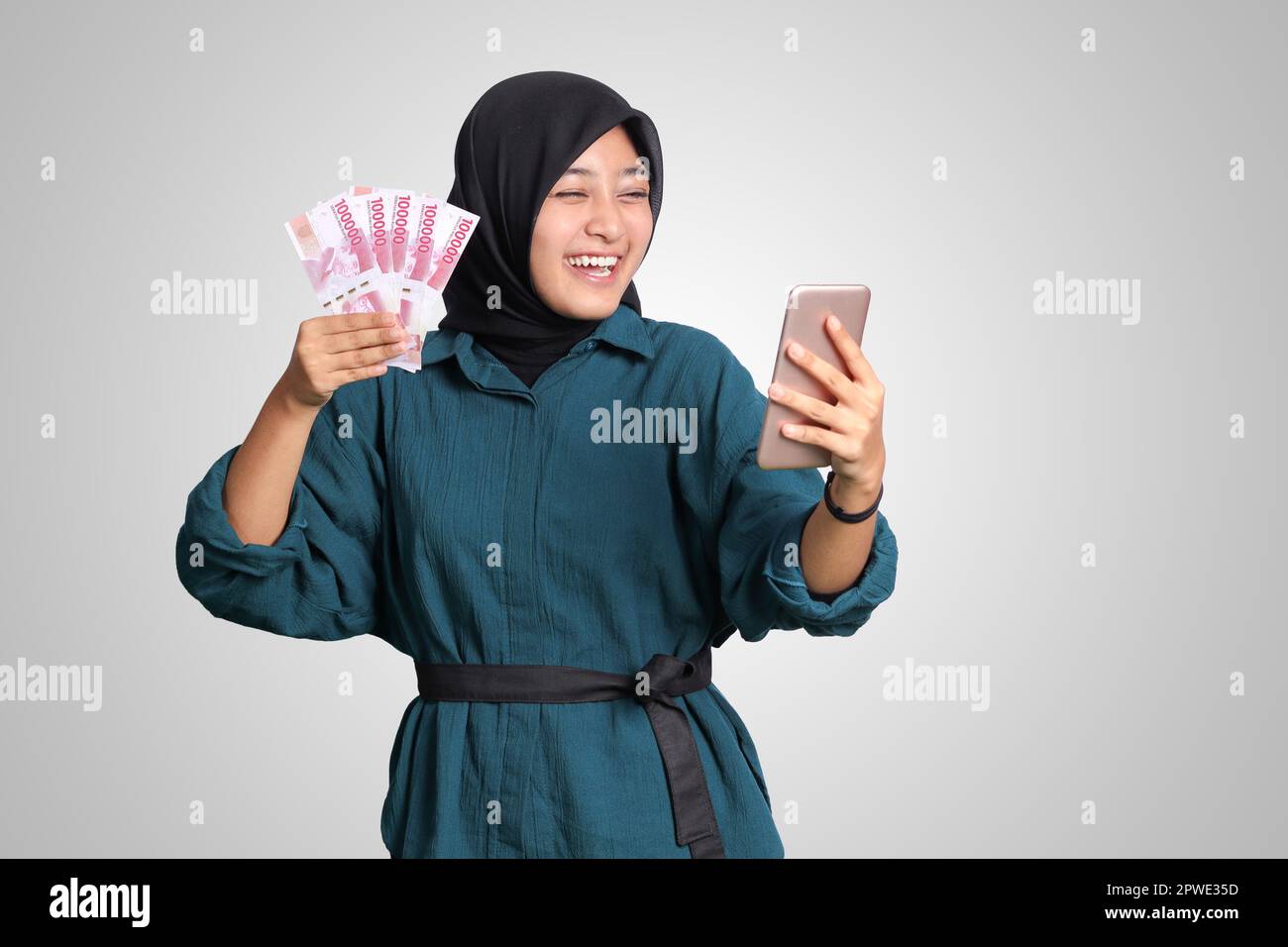 Portrait of excited Asian hijab woman in casual outfit showing one ...