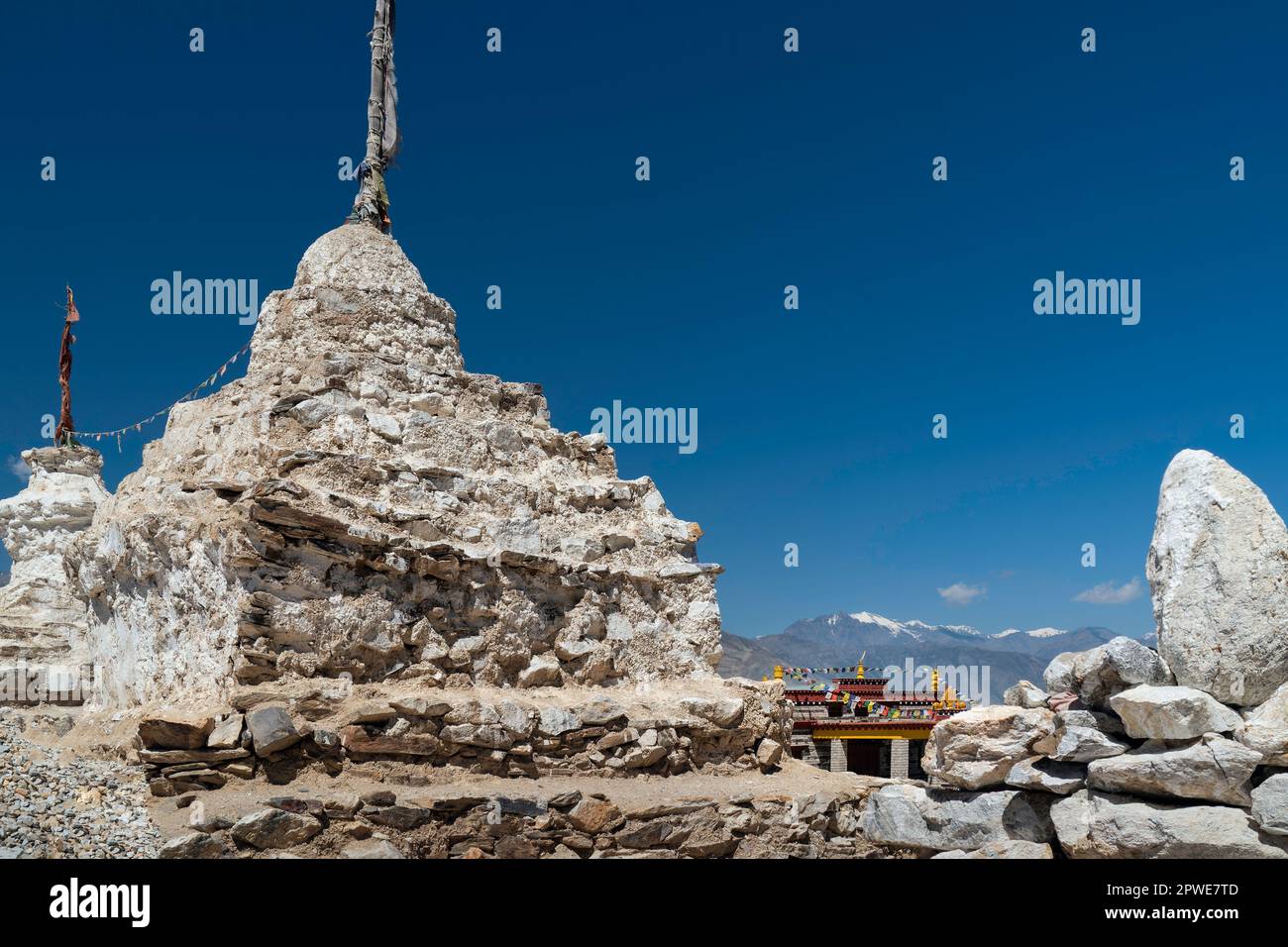 Large Buddhist stupas, prayer flags, rocks and boulders with snow peaks ...