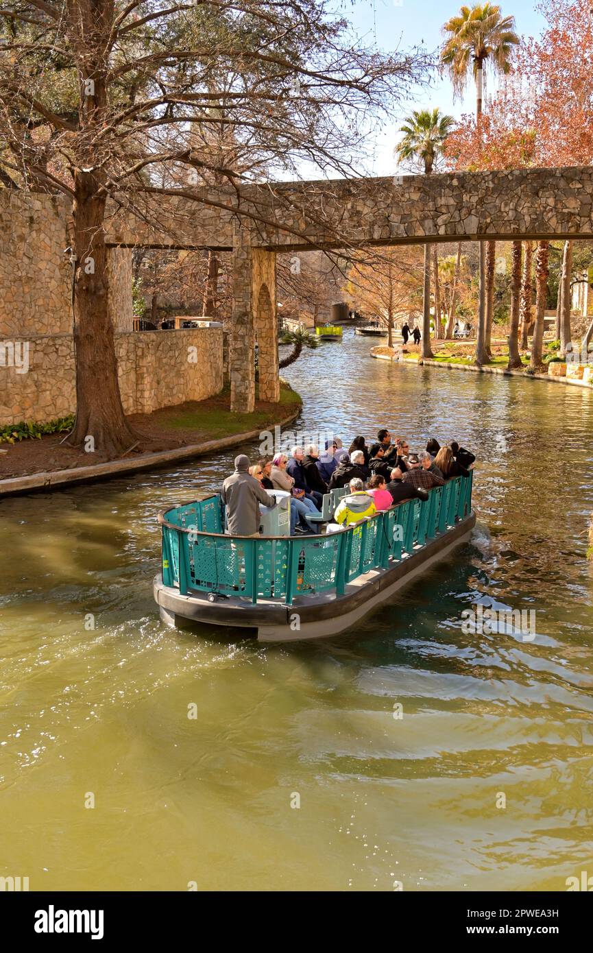San Antonio, Texas, USA - February 2023: Group of people on a tourist sightseeing boat on the river which runs through the centre of the city Stock Photo