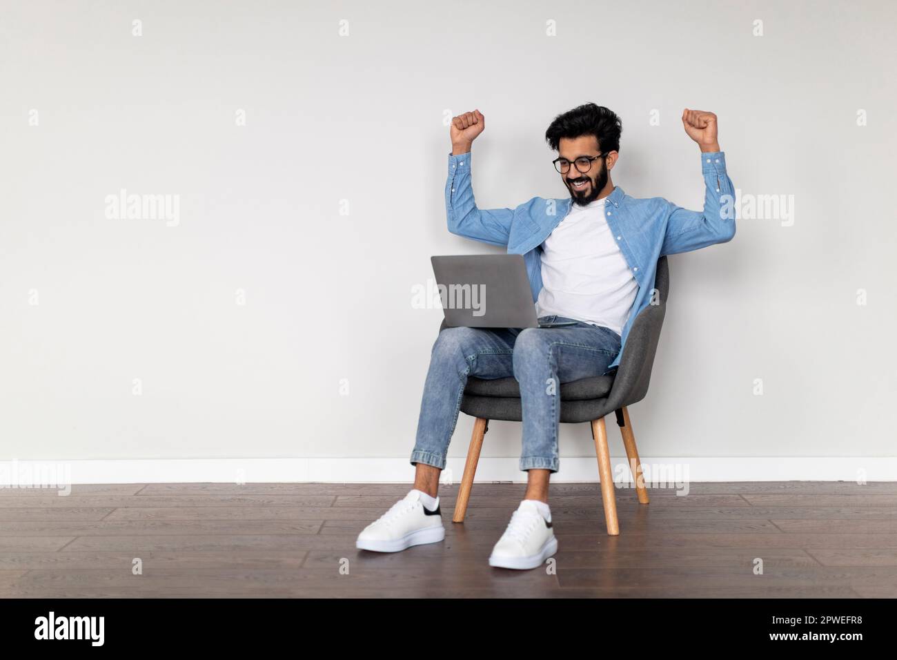 Excited Young Indian Man Using Laptop And Celebrating Success Stock Photo