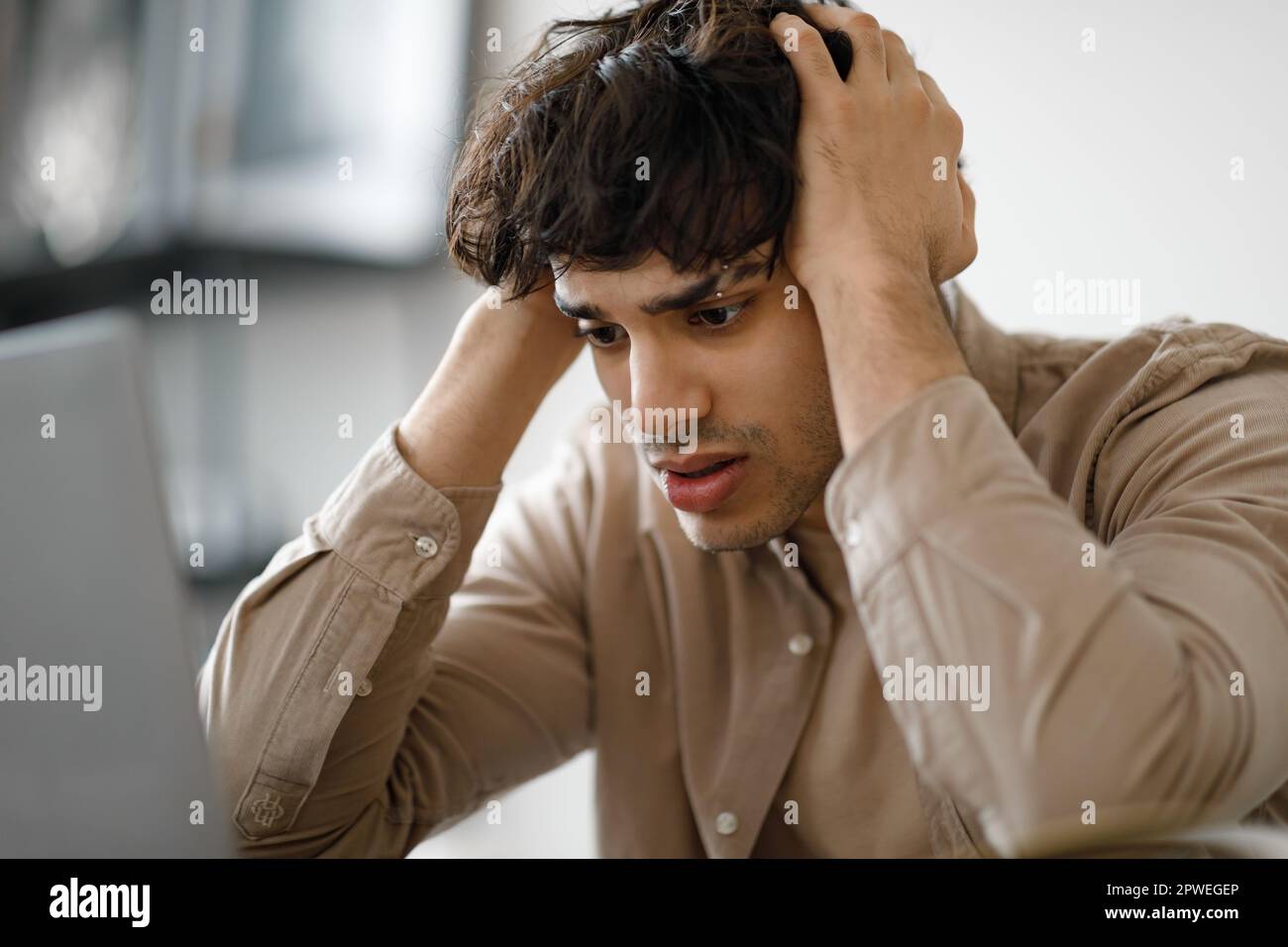 Guy Looking At Laptop Touching Head Having Issue In Office Stock Photo
