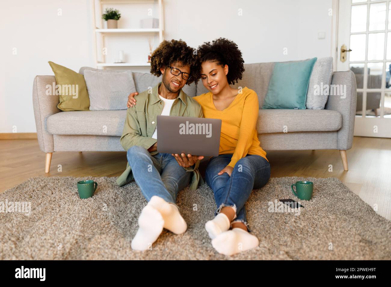 African American Couple Using Laptop Sitting On Floor At Home Stock ...