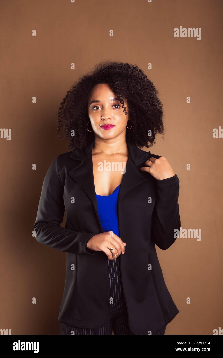 Woman dressed in black blazer standing against brown background