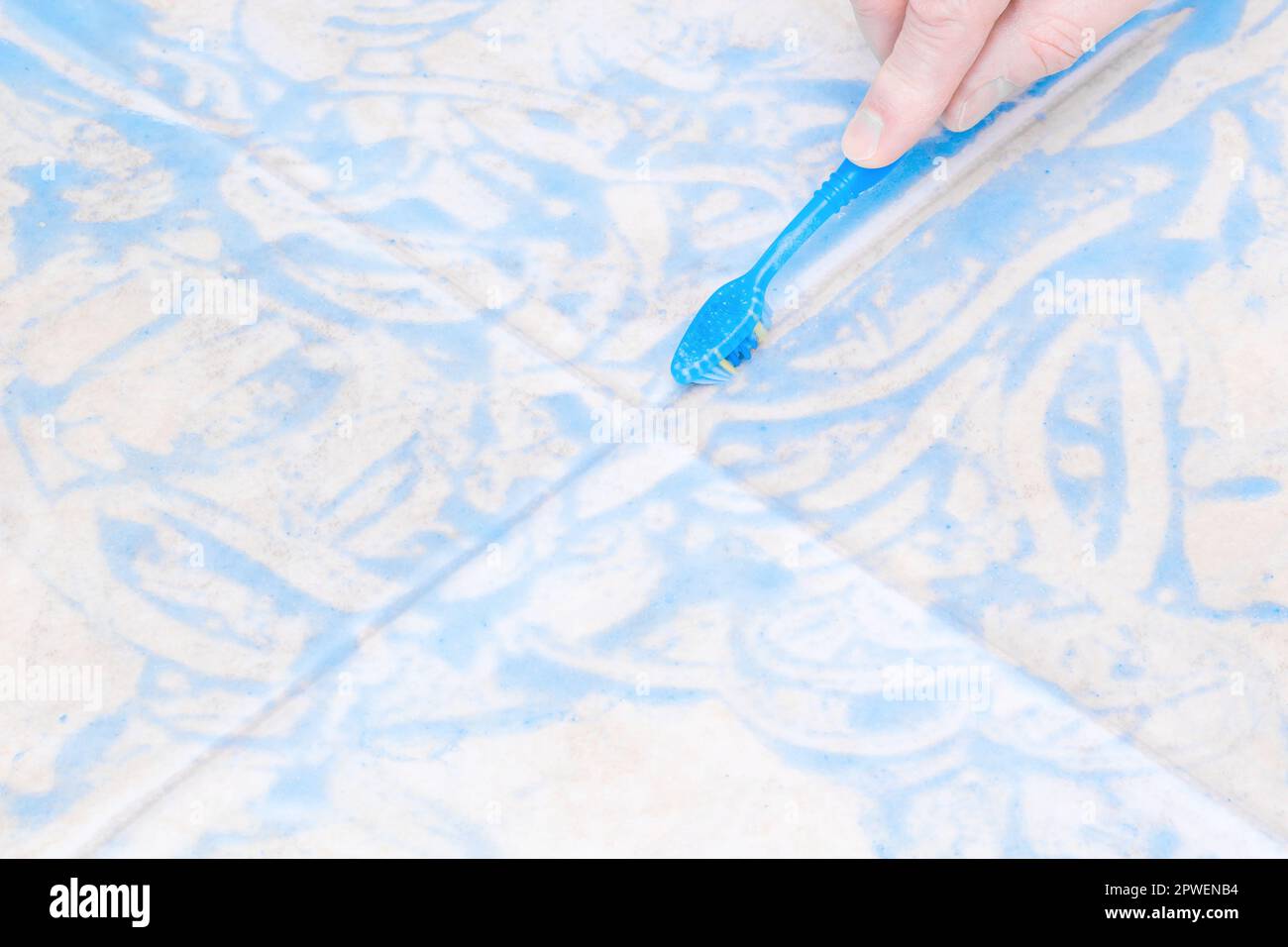 Scrubbing and cleaning floor tiles with a toothbrush Stock Photo
