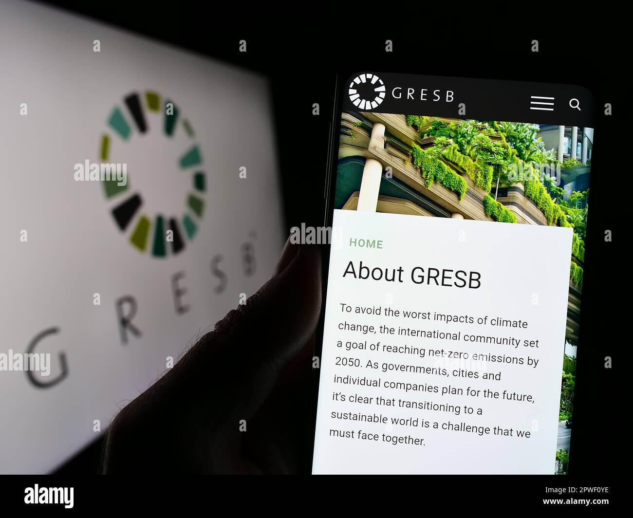 Person holding cellphone with webpage of Dutch real estate ESG foundation GRESB B.V. on screen in front of logo. Focus on center of phone display. Stock Photo