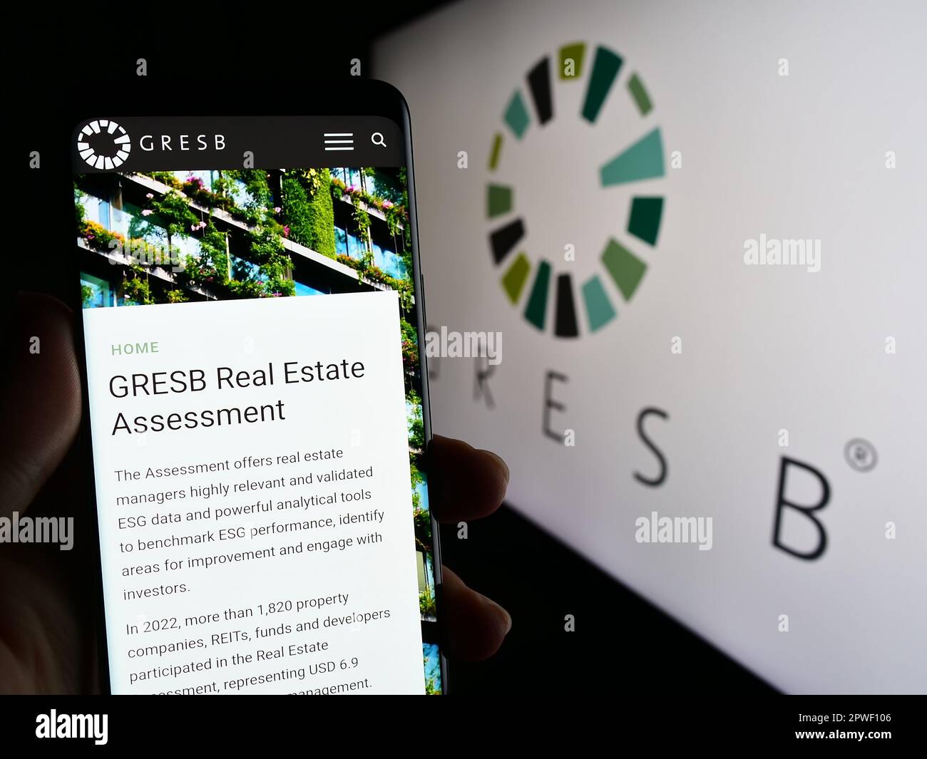 Person holding smartphone with web page of Dutch real estate ESG foundation GRESB B.V. on screen with logo. Focus on center of phone display. Stock Photo