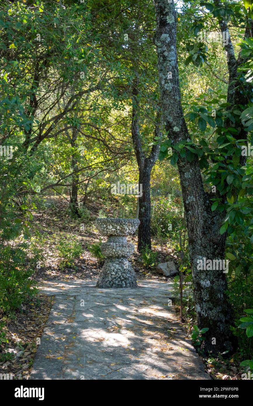 A stone fountain at the end of a path in a lush forest Stock Photo