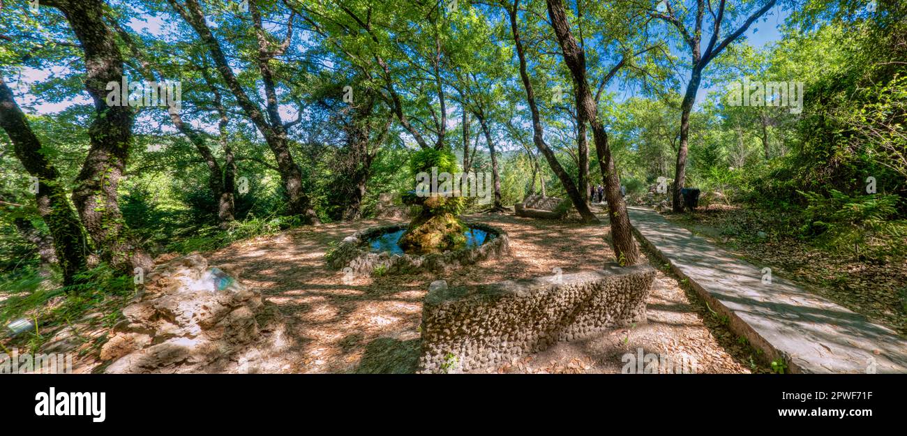 Nice panoramic landscape with a stone fountain next to a path in a lush forest in the Sierra de Cádiz, Spain. Stock Photo