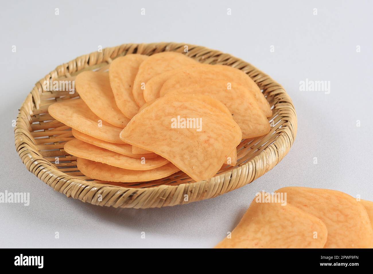 Kerupuk Udang Mentah or Raw Shrimp Crackers on Bamboo Rattan pLate on White Table Stock Photo
