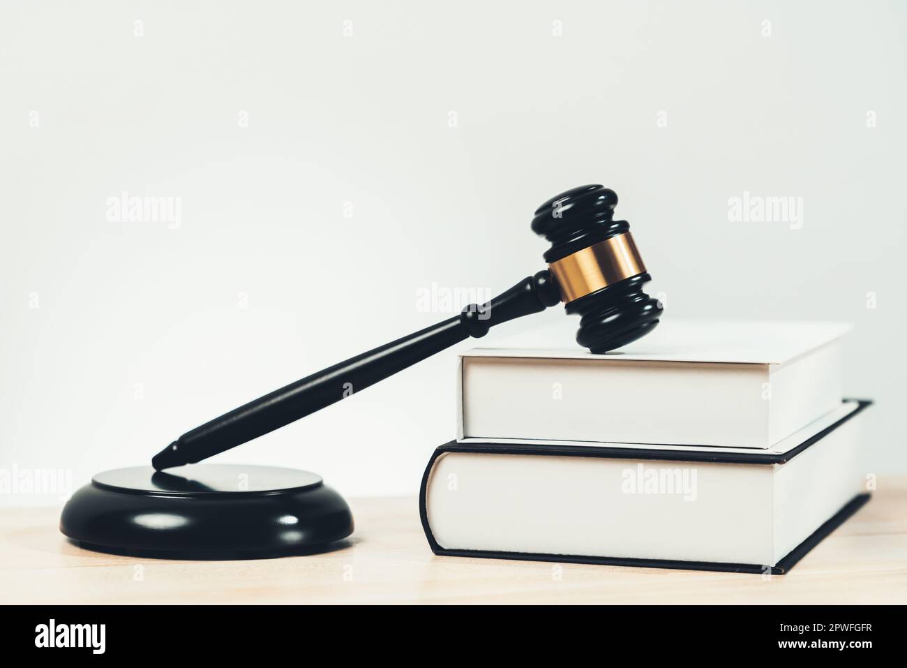 Closeup wooden gavel hammer and law book in empty law firm or white lawyer office background as