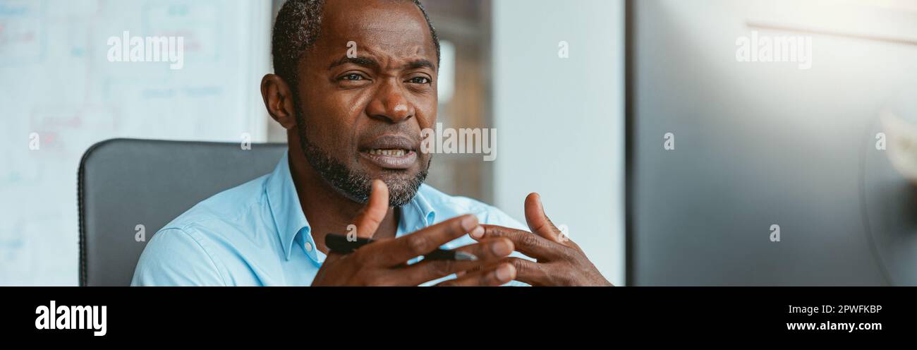 Busy african businessman making videocall to client while sitting in modern office Stock Photo