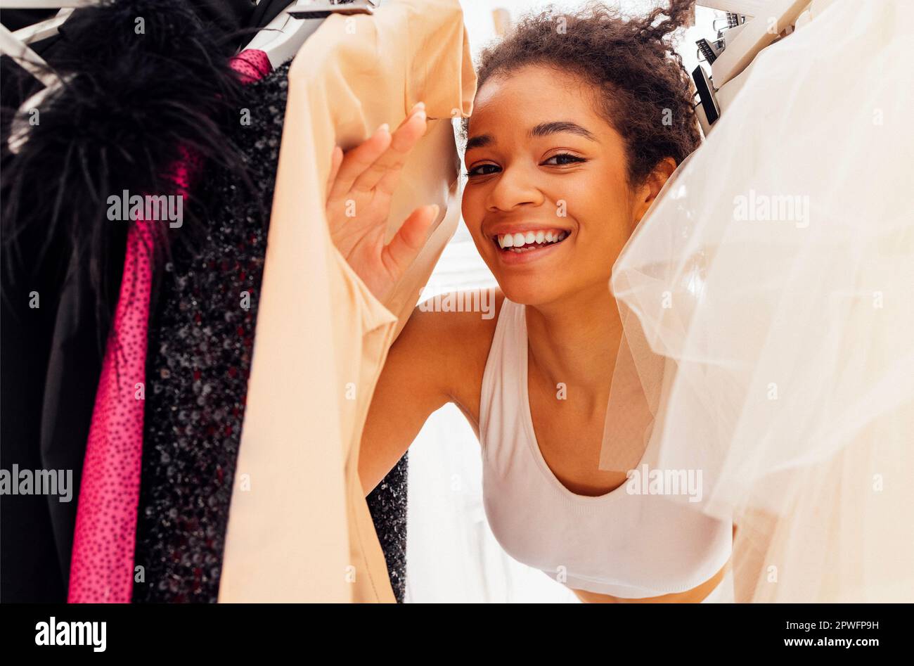 Clothes, retail and happy black woman shopping in a boutique, laugh and  smile while feeling fabric. Fun, fashion and girl customer excited for clothing  sale, discount or outfit choice in store