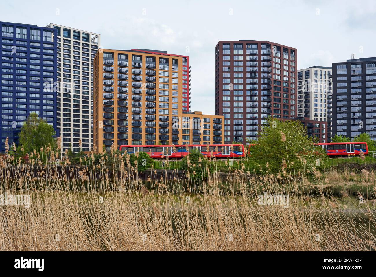 The new London City Island apartment complex and a Docklands Light Railway train, viewed from the banks of the River Lea, East London UK Stock Photo