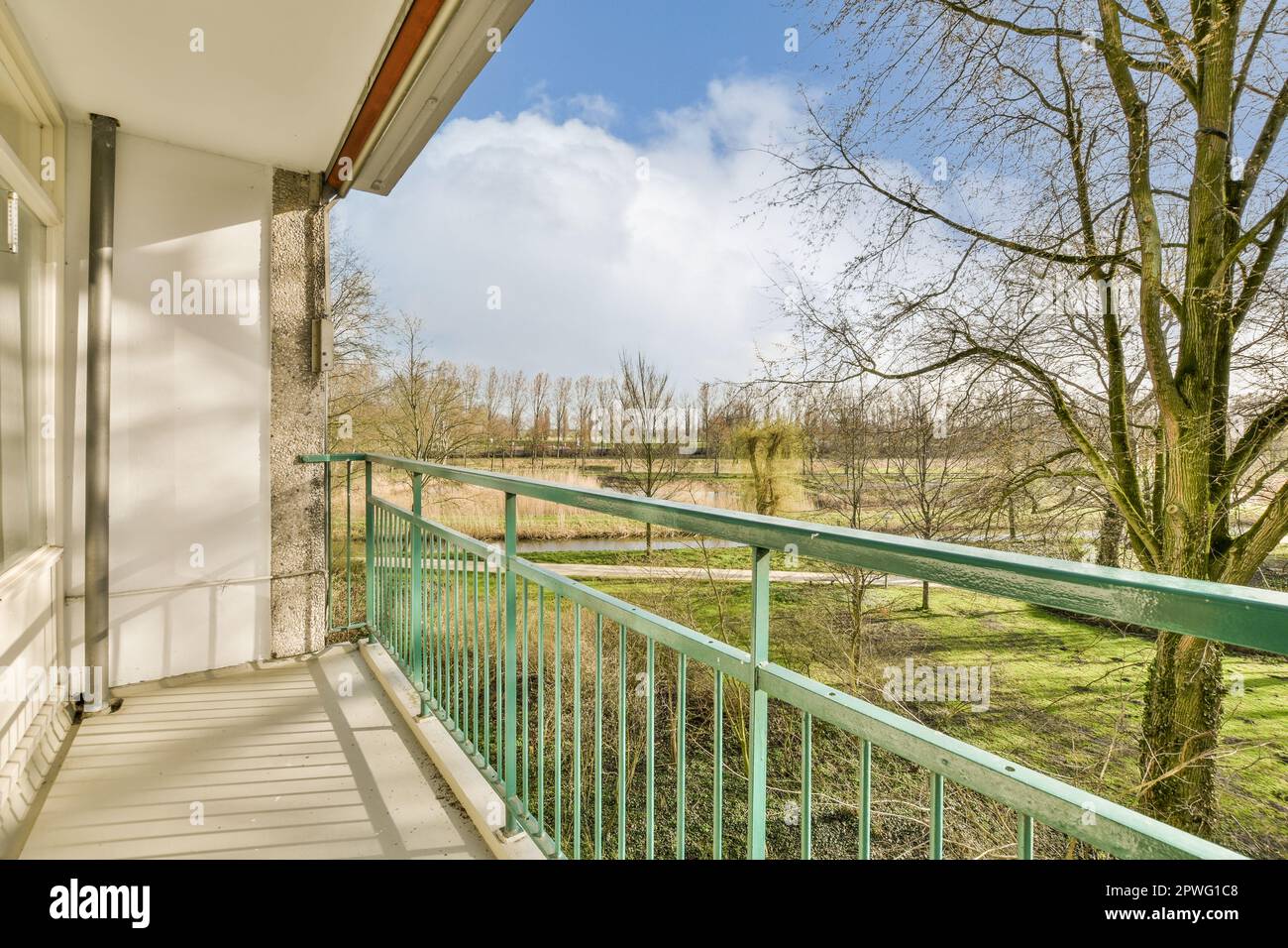 a balcony with green railings and trees in the distance, on a sunny blue sky day that's just overcast Stock Photo