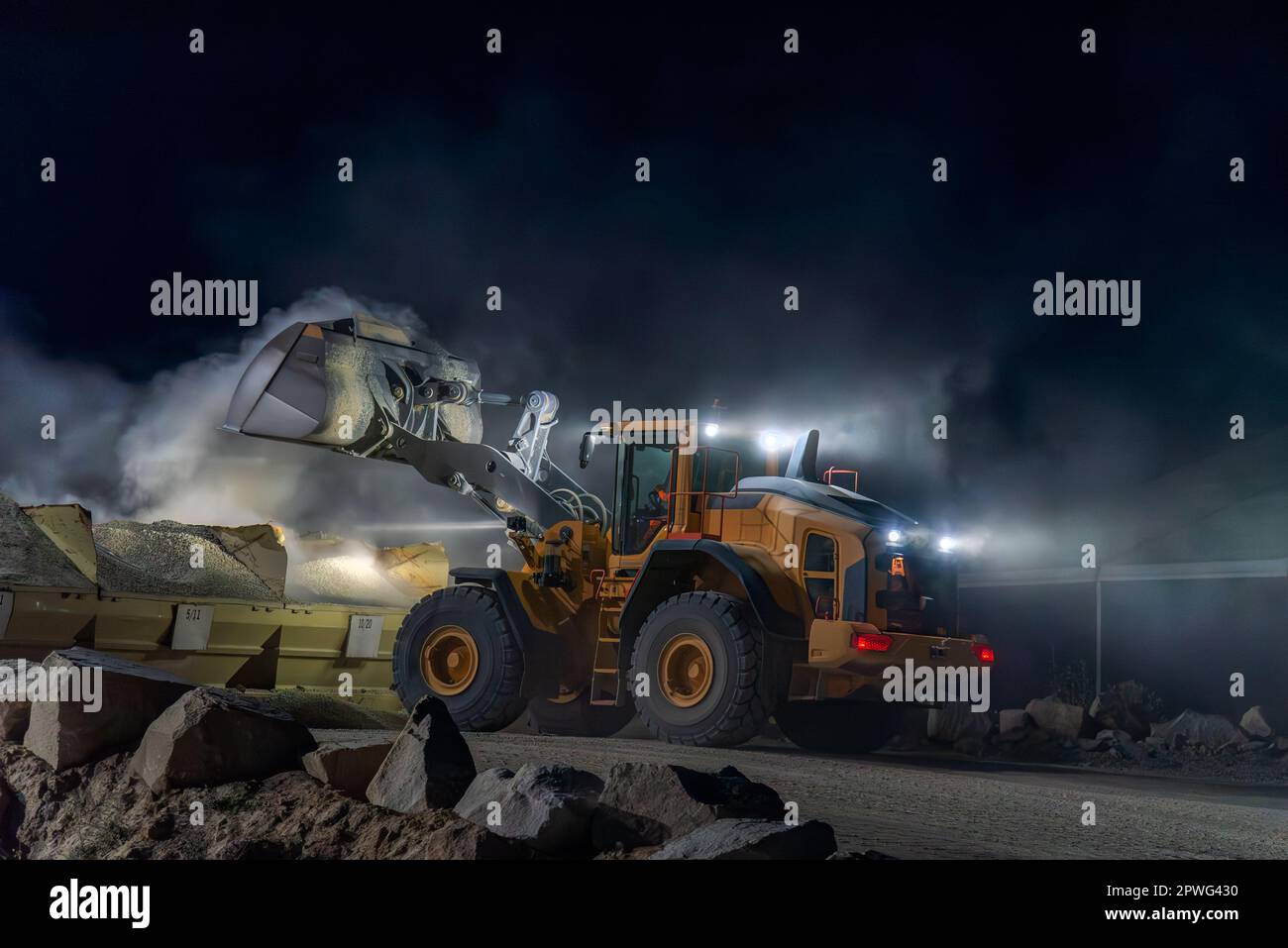 Heavy construction and mining machinery unloading gravel into silos on the night shift. Close-up. Stock Photo