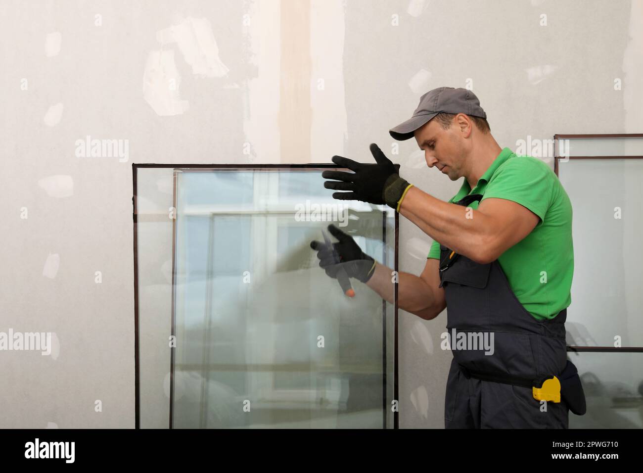 Worker in uniform preparing double glazing window for installation indoors Stock Photo