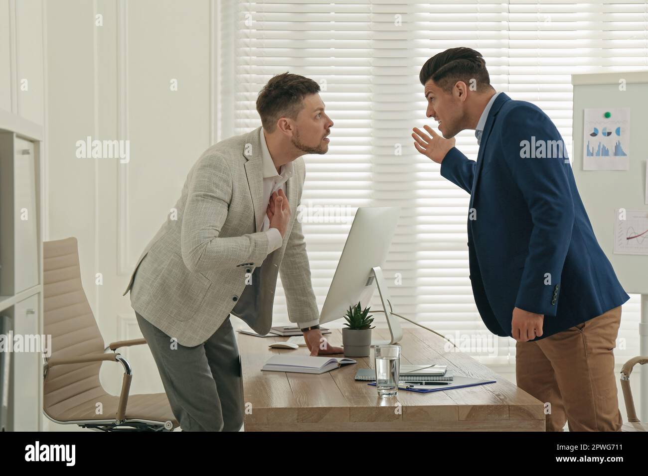 Colleagues fighting at table in office. Workplace conflict Stock Photo