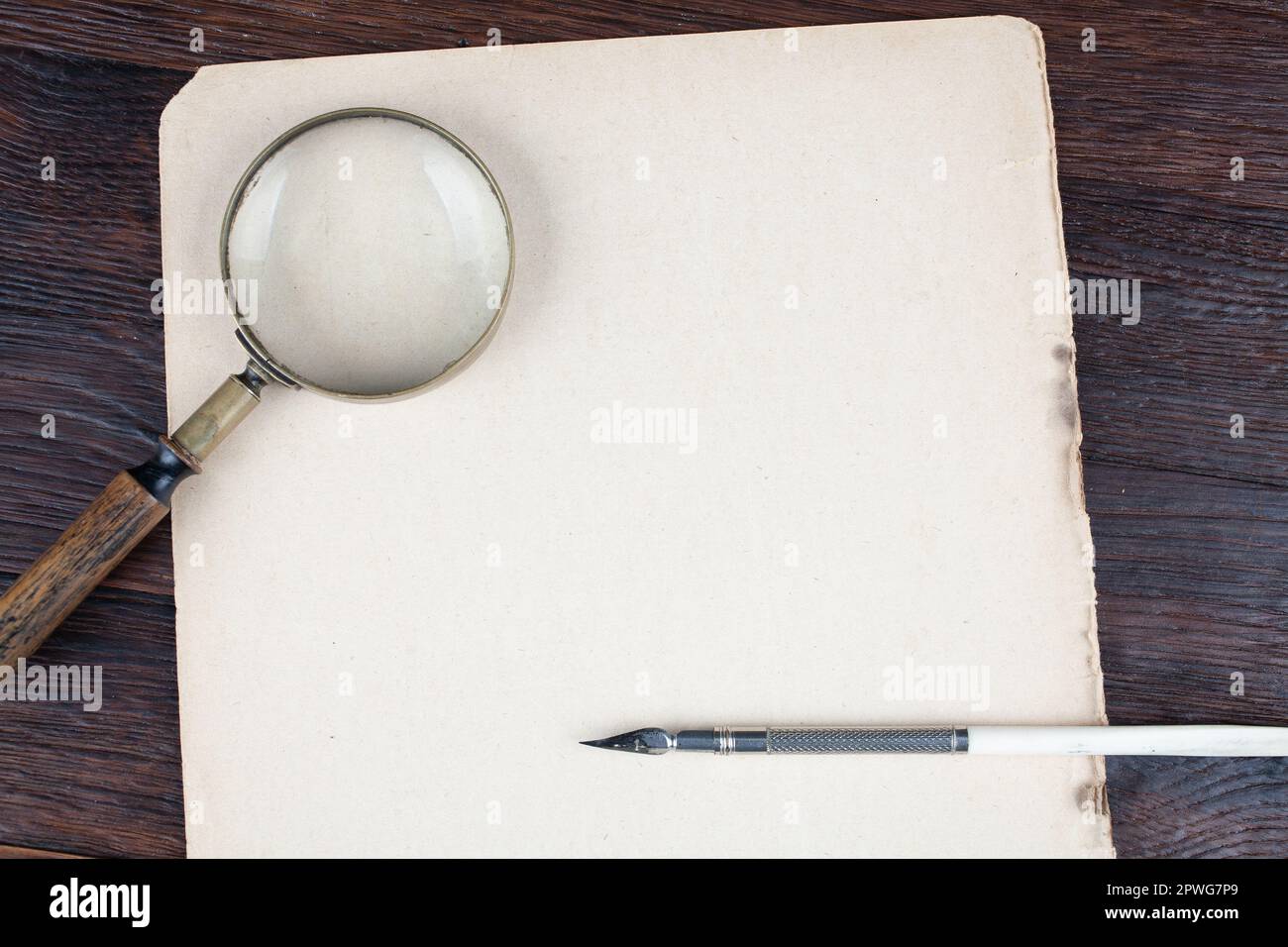 Antique vintage magnifying glass with old ink pen on paper background ...