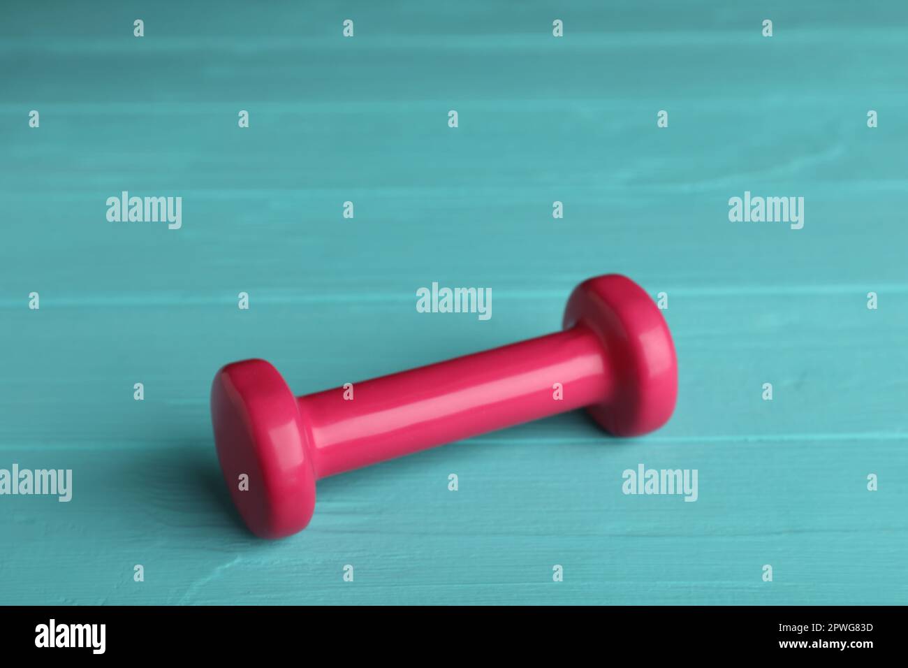 Pink vinyl dumbbell on turquoise wooden table Stock Photo