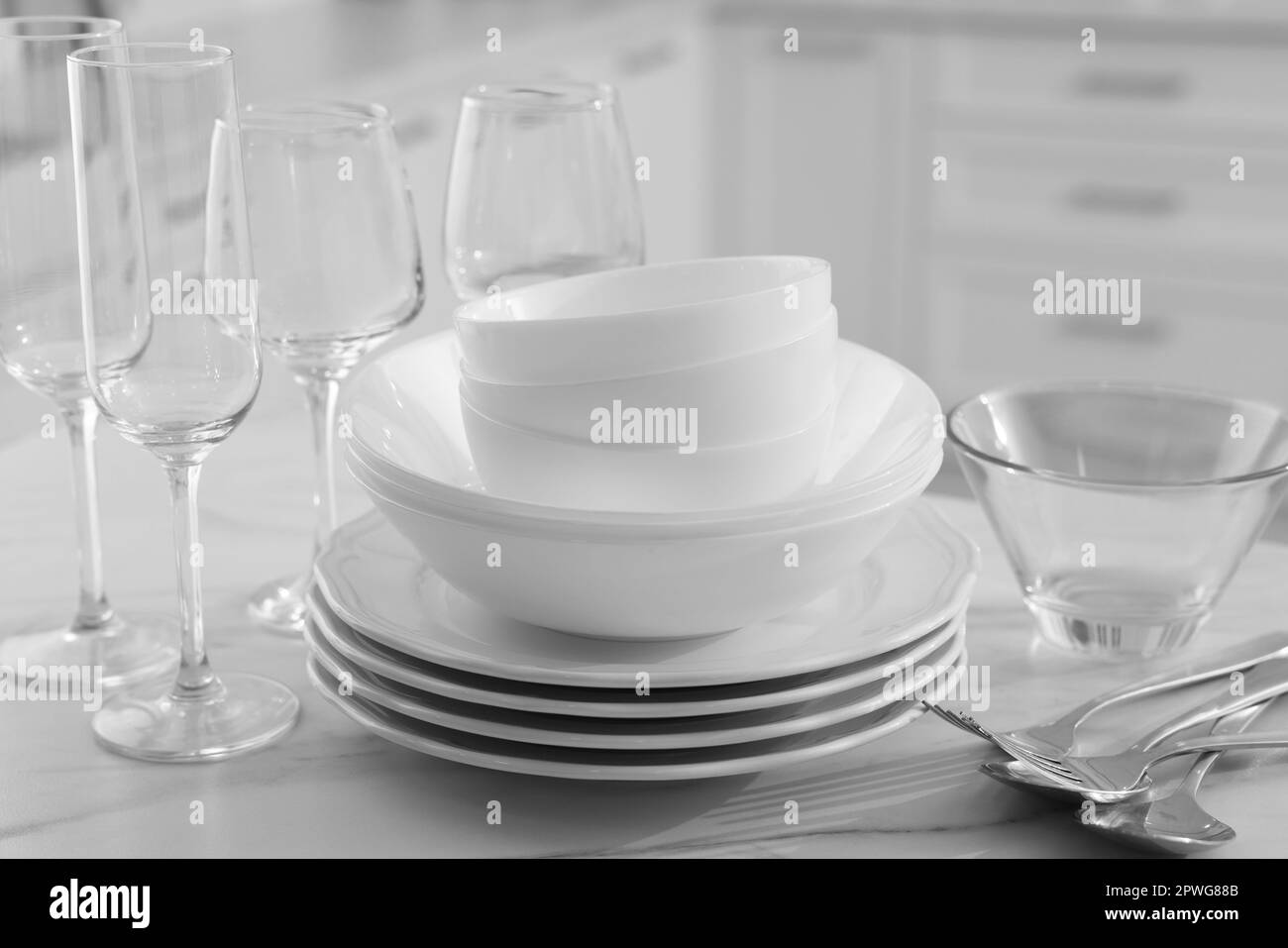 Different clean dishware, cutlery and glasses on white marble table in kitchen, closeup Stock Photo
