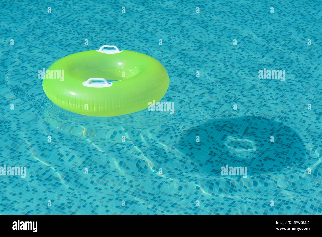 Light green inflatable ring floating in swimming pool. space for text ...