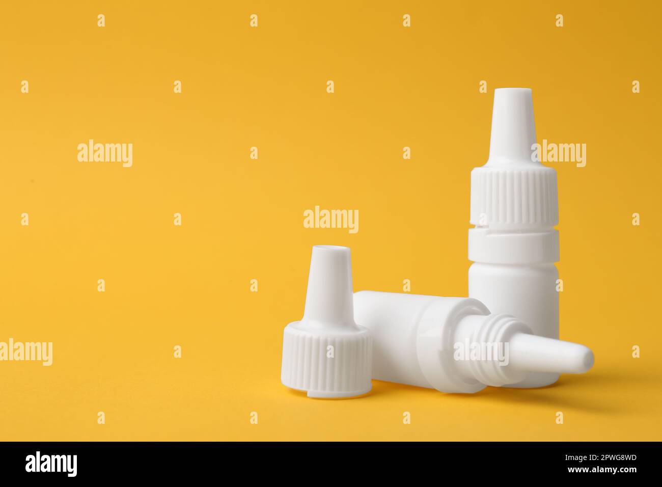 Bottles of medical drops on yellow background. Space for text Stock Photo