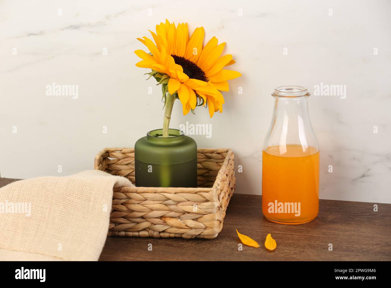 https://c8.alamy.com/comp/2PWG9M6/vase-with-beautiful-sunflower-in-wicker-basket-and-bottle-of-orange-juice-on-wooden-table-2PWG9M6.jpg