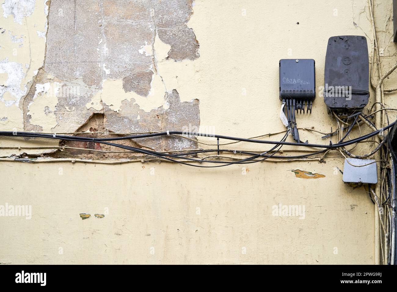 Old telephone cables and junction boxes attached to shabby old wall with peeling cream coloured paint Stock Photo