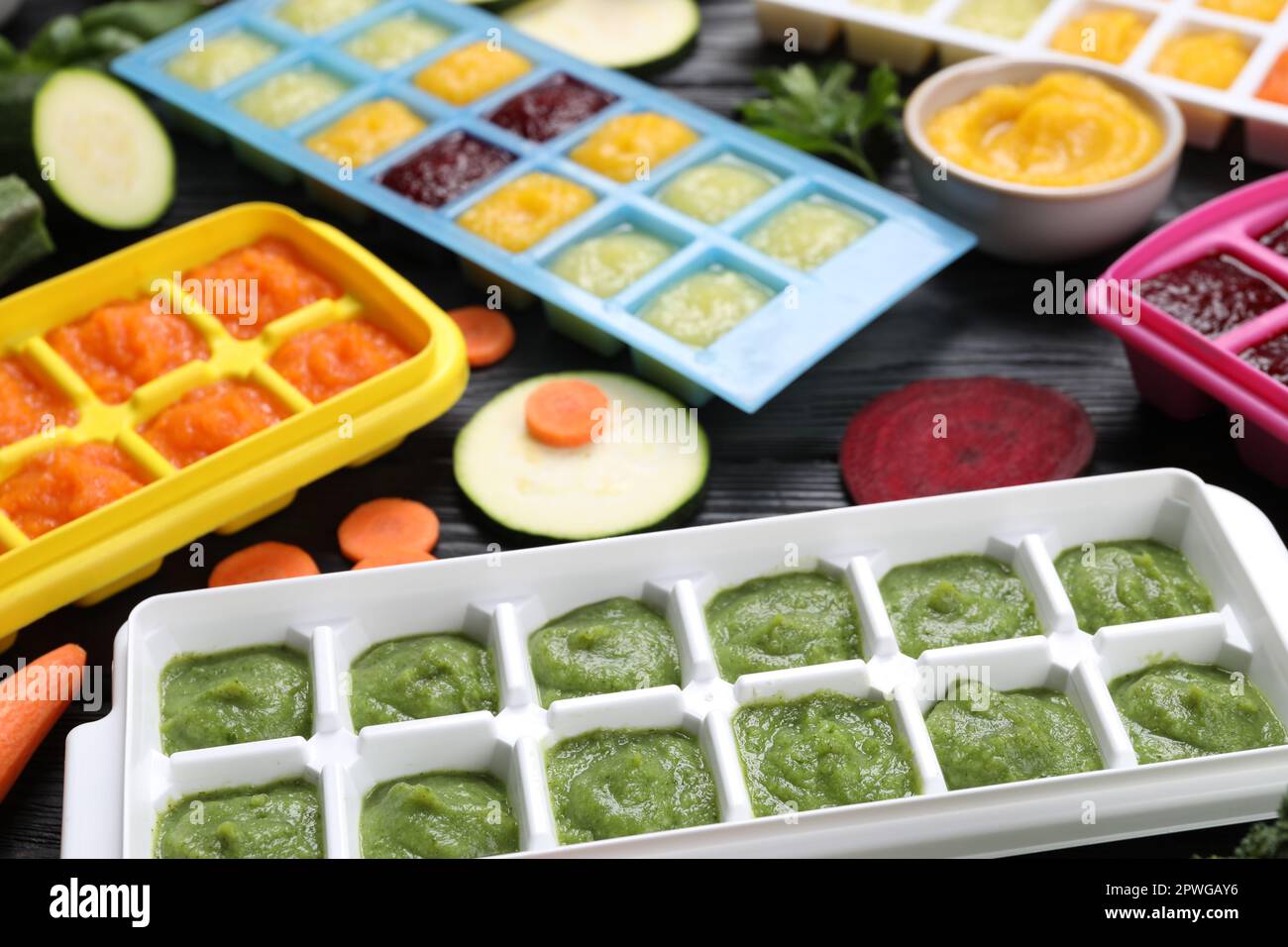 Different frozen purees in ice cube trays and ingredients of black