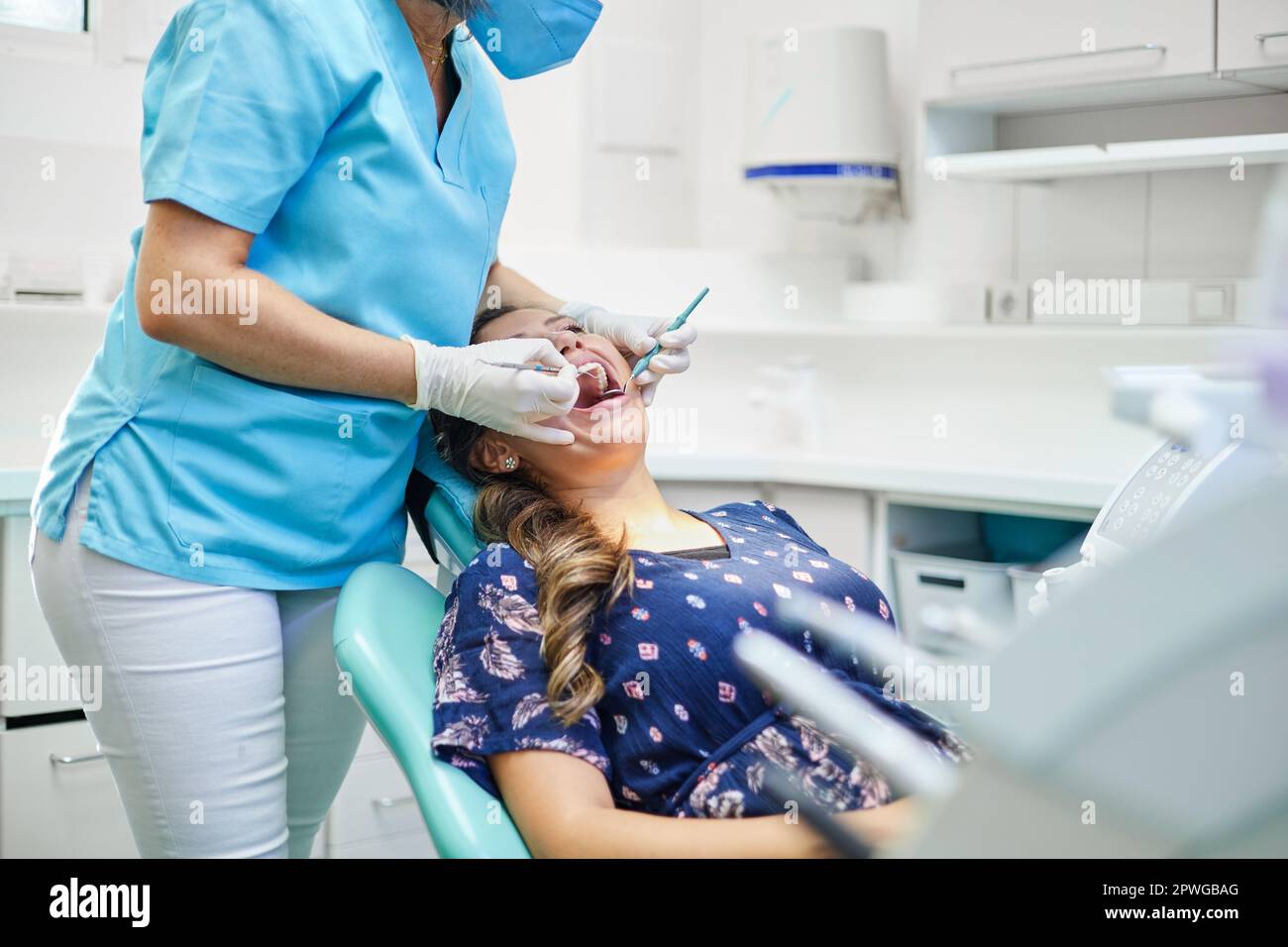 Crop dentist in uniform and latex gloves using probe and mirror to