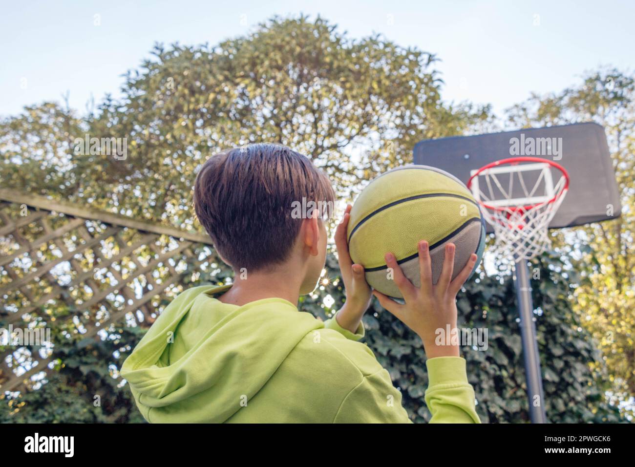 Back view of a teenager shooting a basketball into the hoop Stock Photo