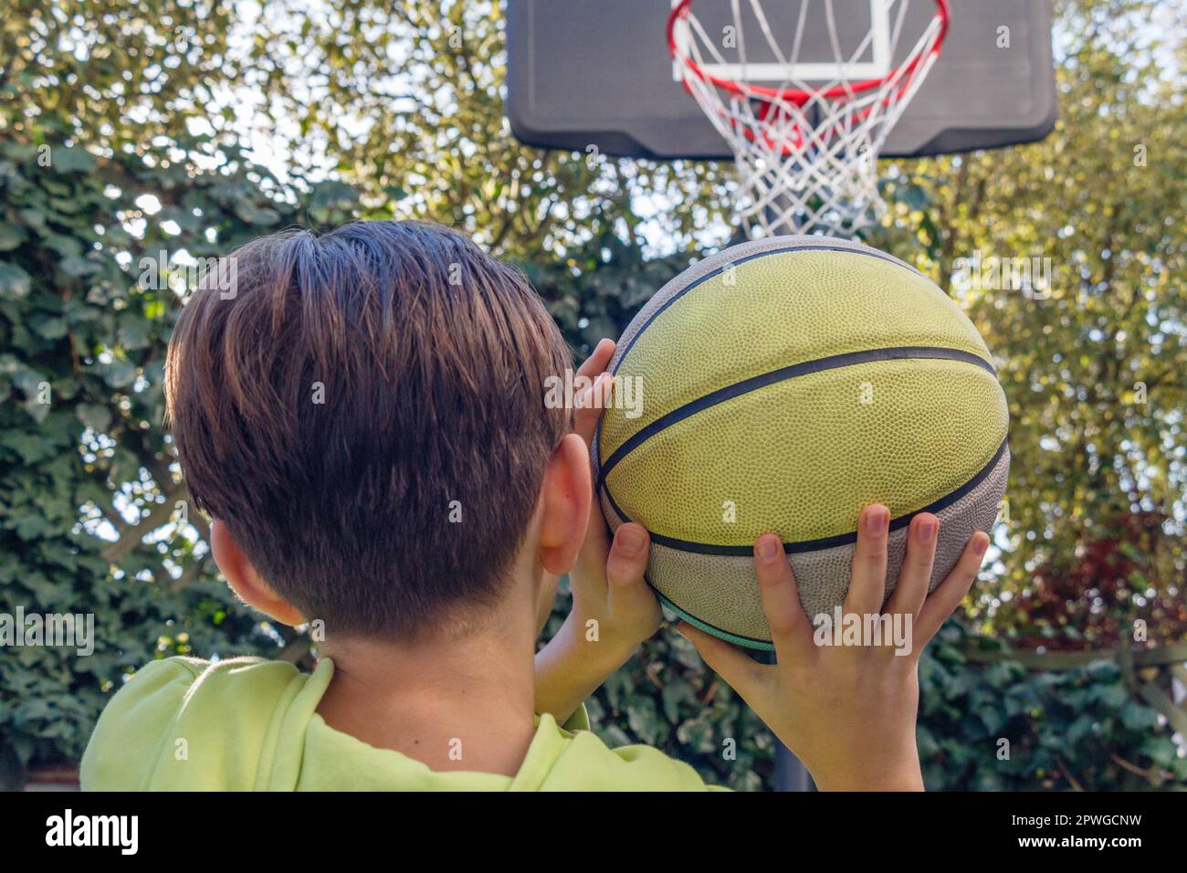 Closeup of a teenager throwing a basketball into the hoop. Back view