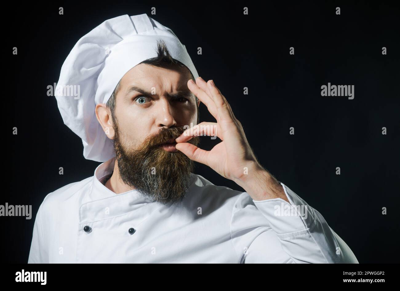 Bearded chef, cook or baker making tasty approval gesture by kissing fingers. Chef in uniform with perfect sign. Professional cook in chef hat shows Stock Photo