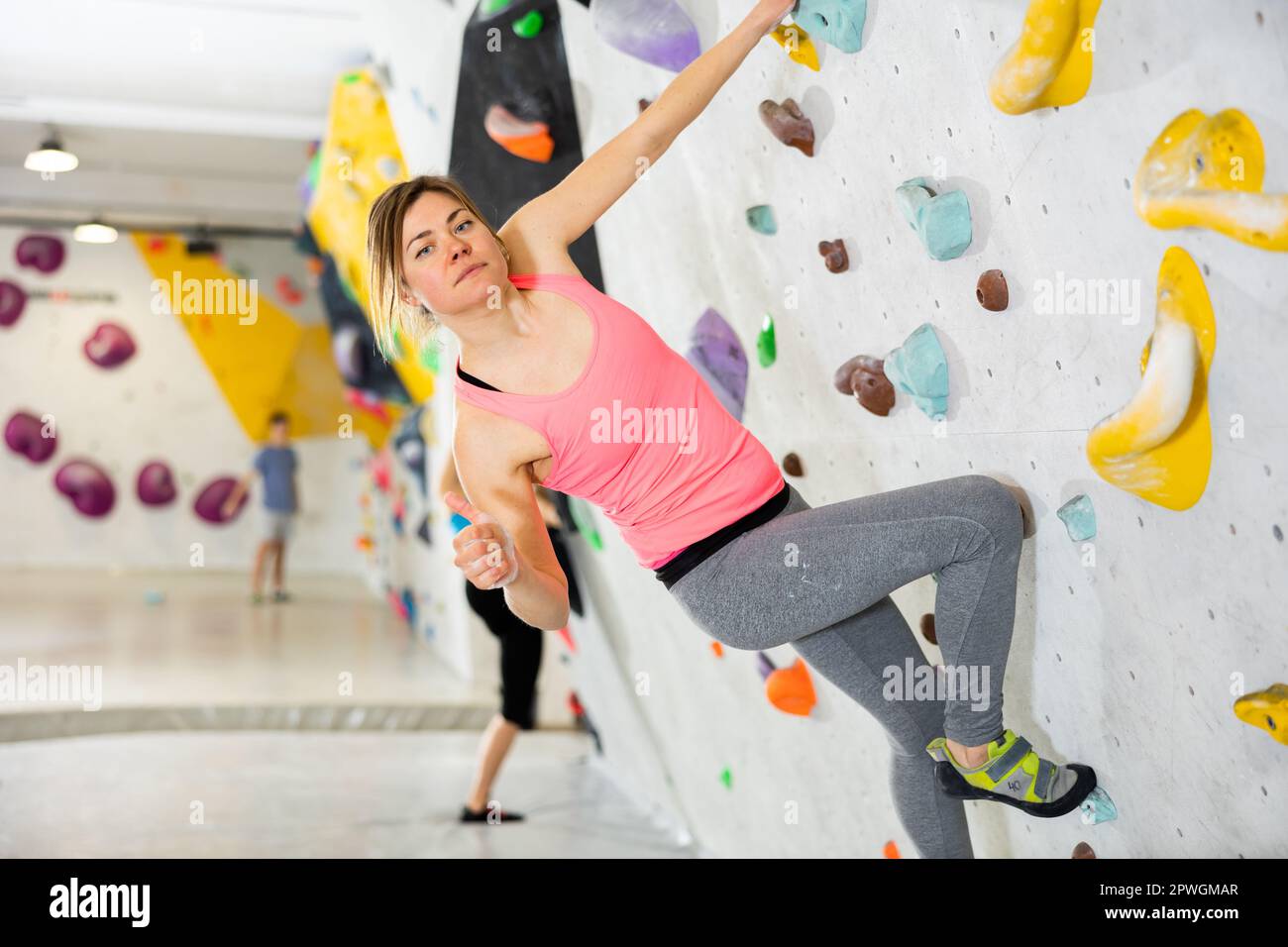 Young man making thumb up gesture while climbing in bouldering gym Stock Photo