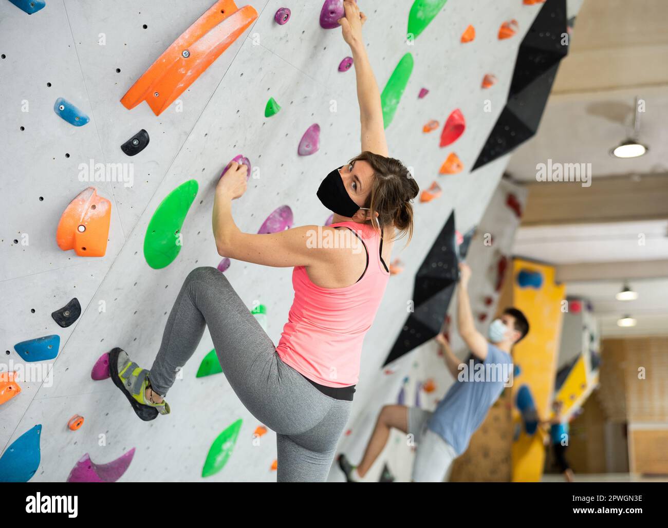 Woman in protective mask training at bouldering gym without special ...