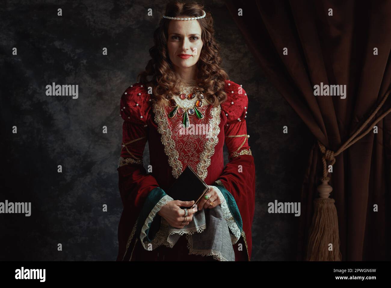 medieval queen in red dress with book and handkerchief on dark gray ...