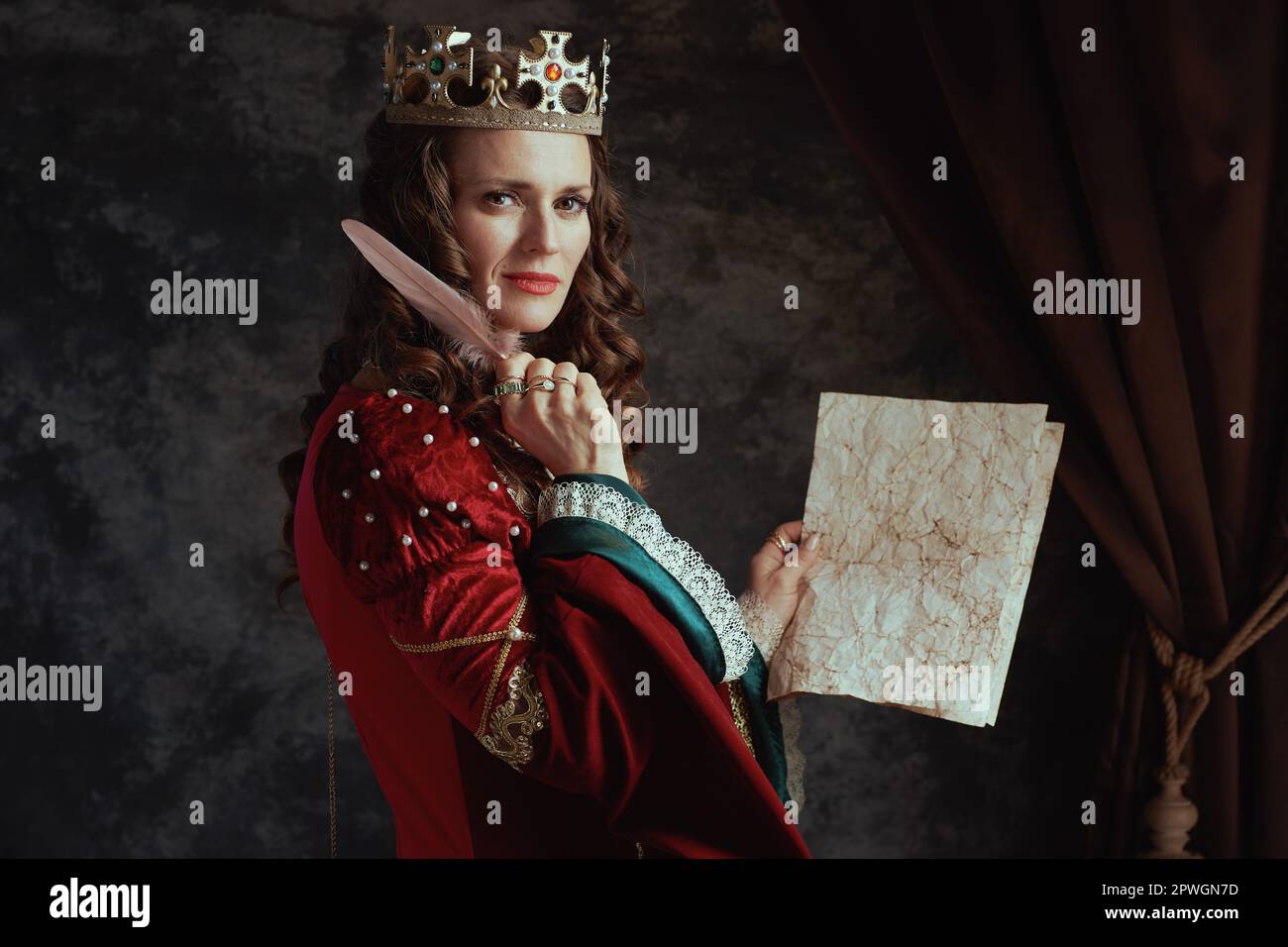 medieval queen in red dress with parchment and crown on dark gray ...