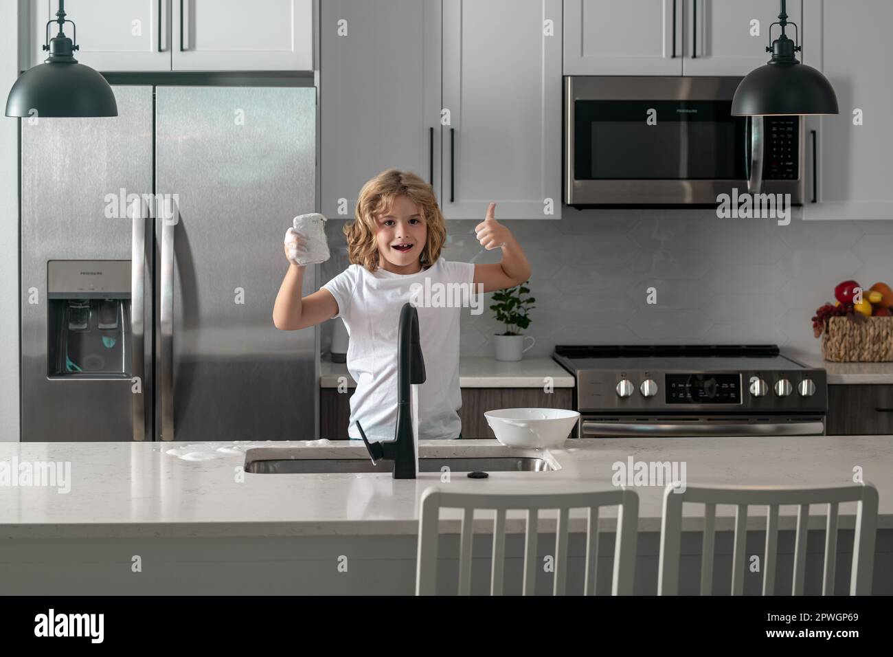 Funny twin boys helping in kitchen with washing dishes. Children having fun with housework. Kid