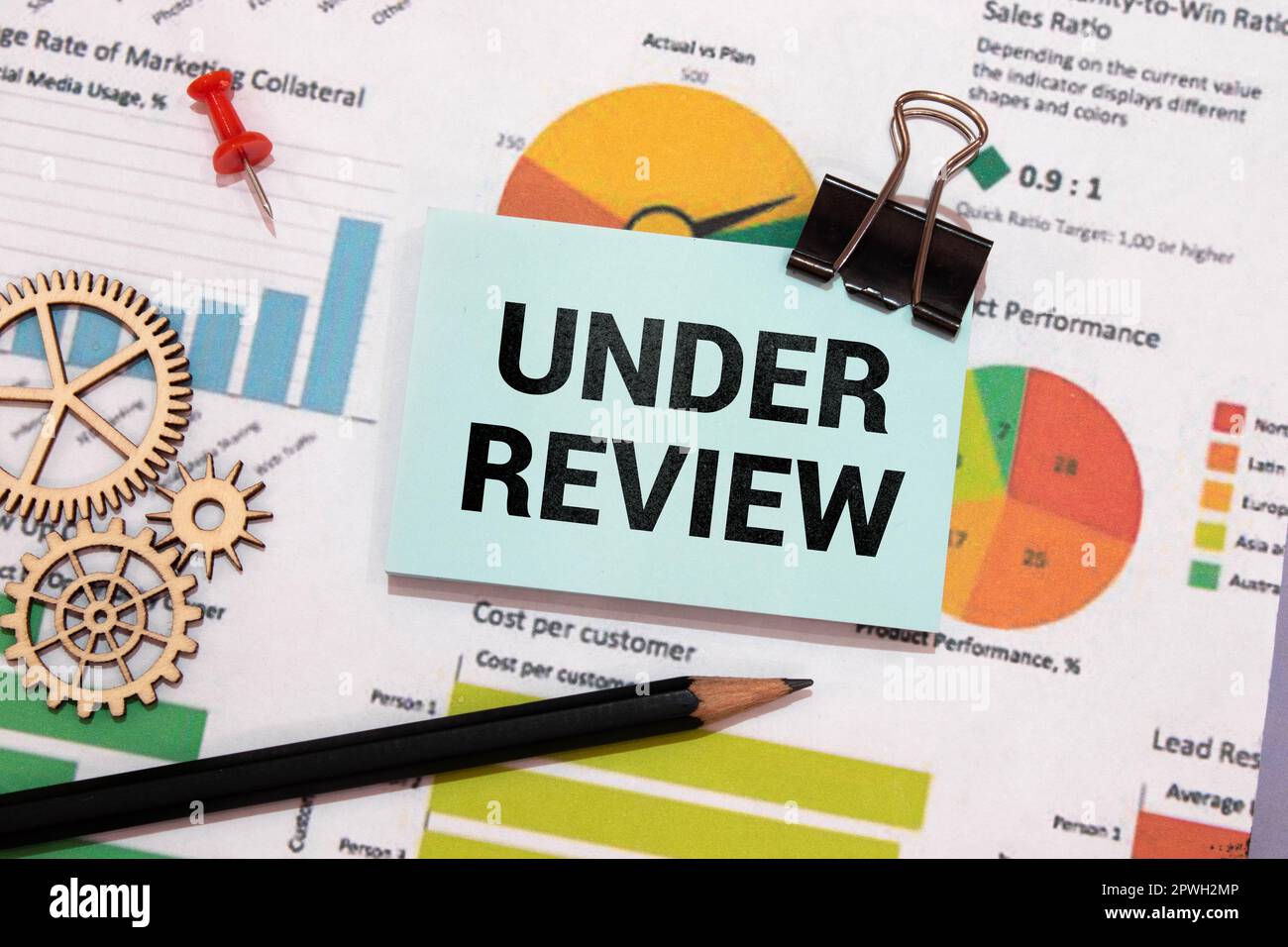under review. text is written on white paper on a wooden table Stock Photo