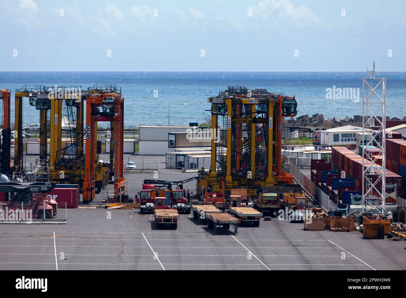 Le Port, Reunion Island - Marsh 08 2017: Container loaders and othe machineries from the Port Réunion Est, a commercial dock located in the seashore c Stock Photo