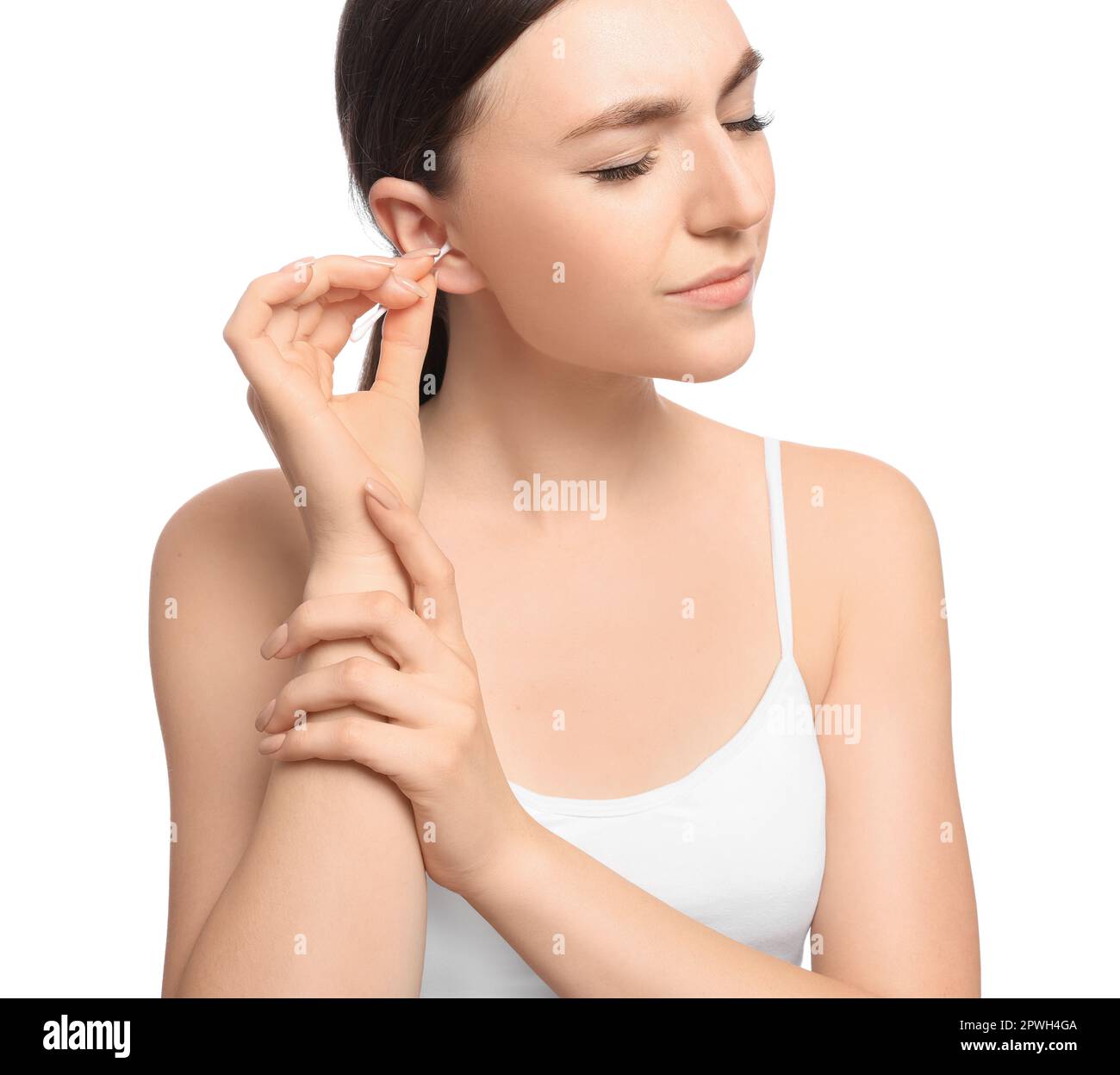 Young woman cleaning ear with cotton swab on white background Stock