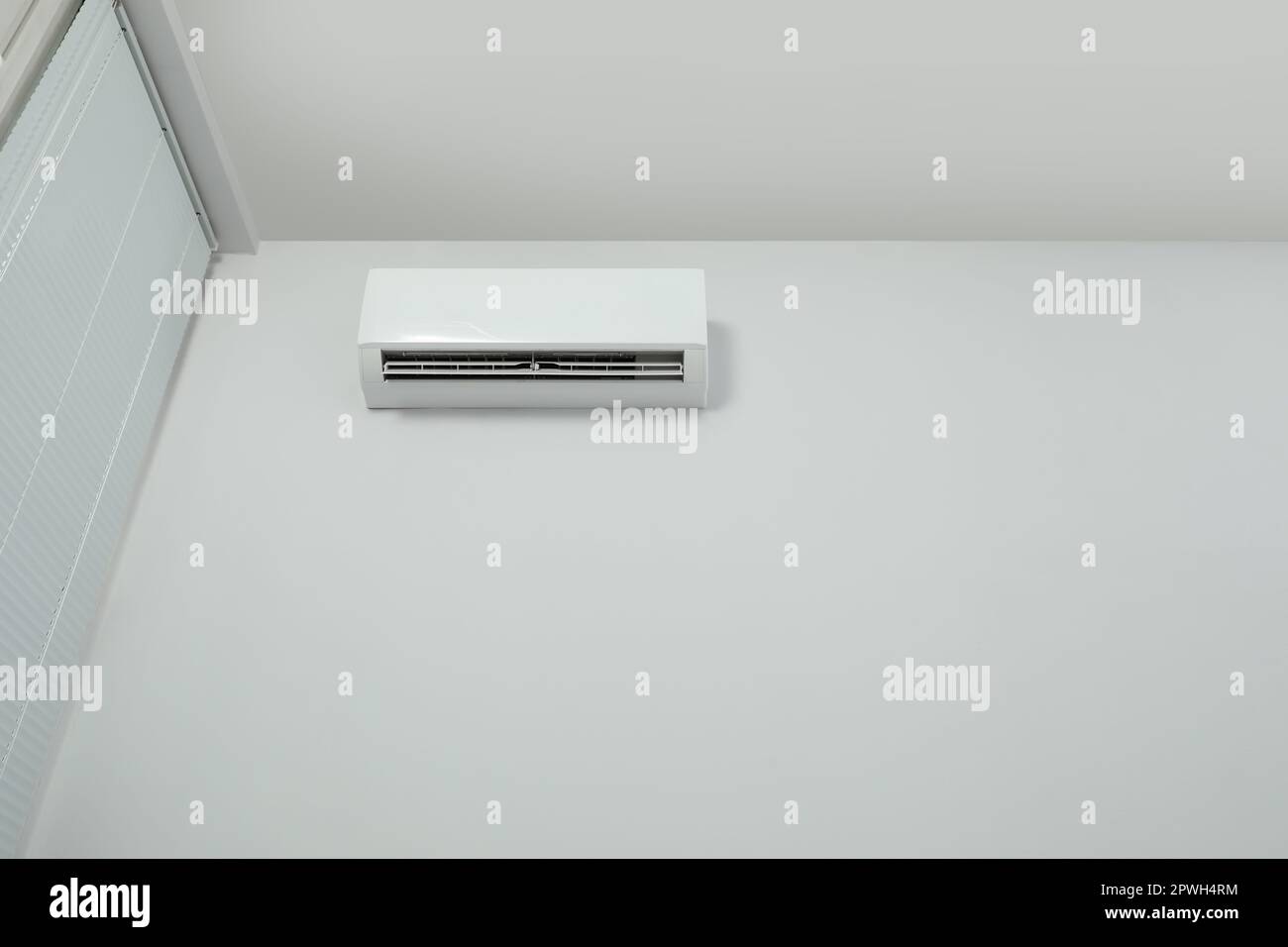 Modern air conditioner on white wall indoors, low angle view. Space for ...