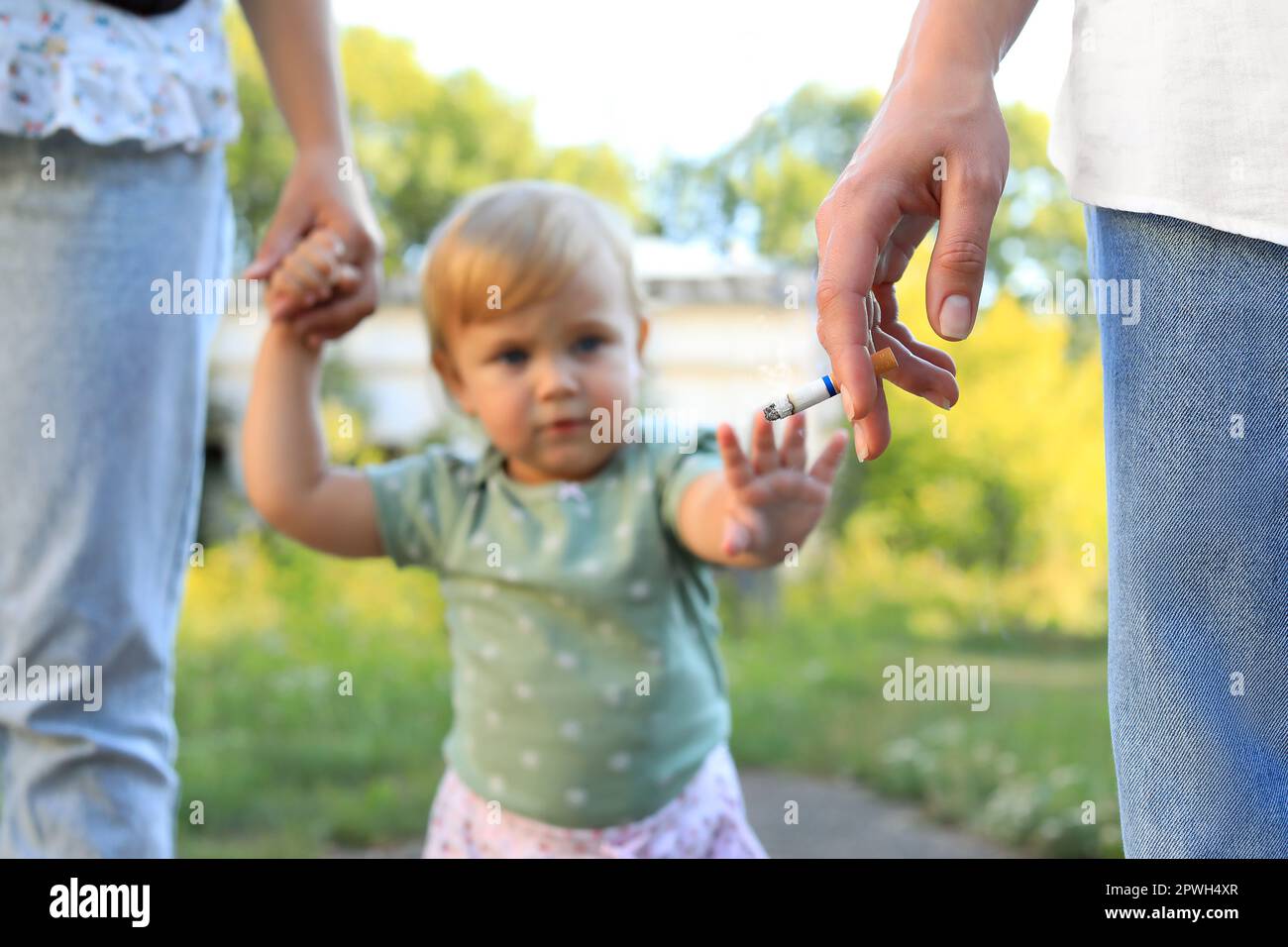 Woman smoking cigarette in public place outdoors, closeup. Don't smoke