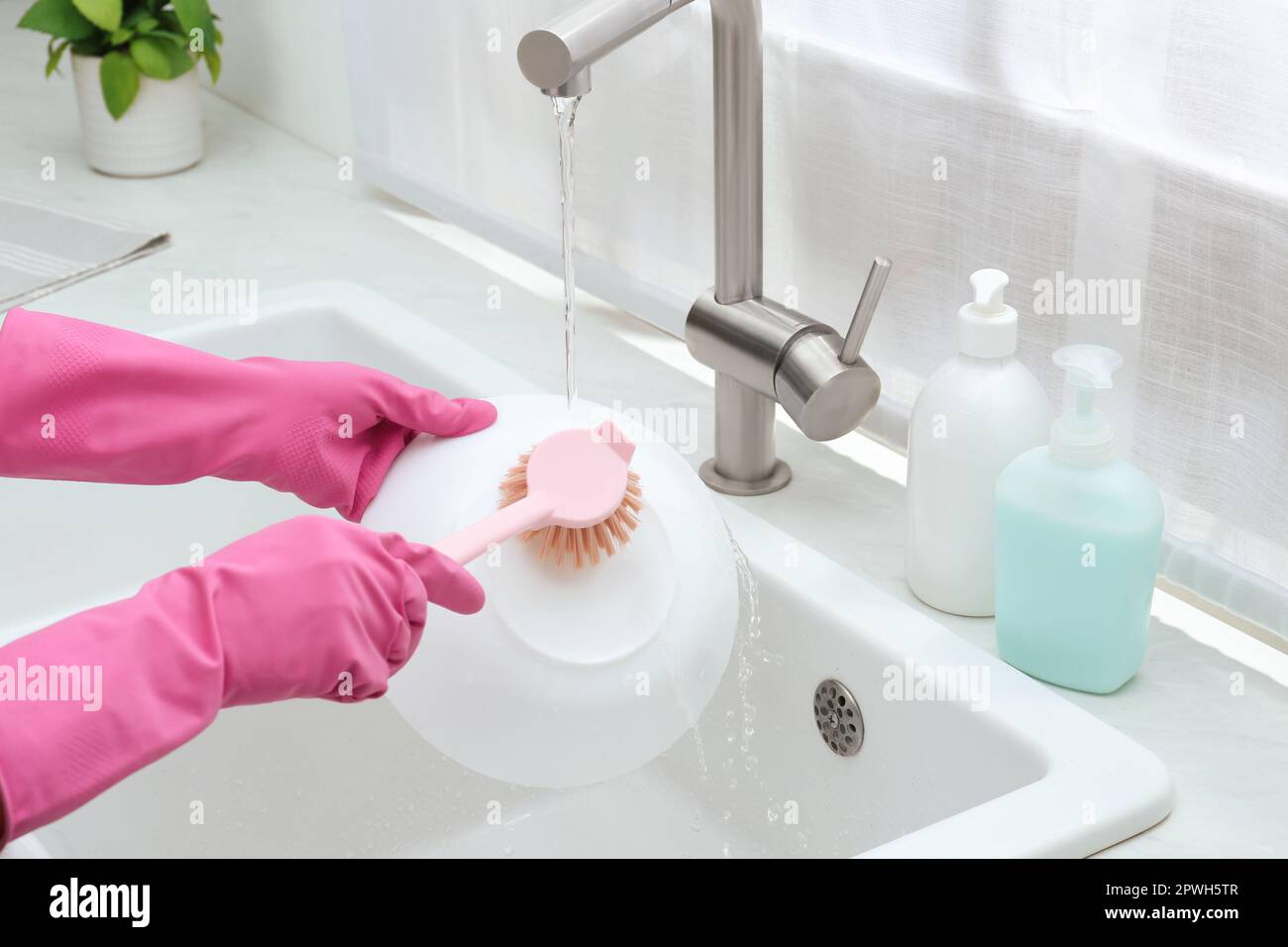https://c8.alamy.com/comp/2PWH5TR/woman-washing-bowl-with-brush-above-sink-in-kitchen-closeup-2PWH5TR.jpg